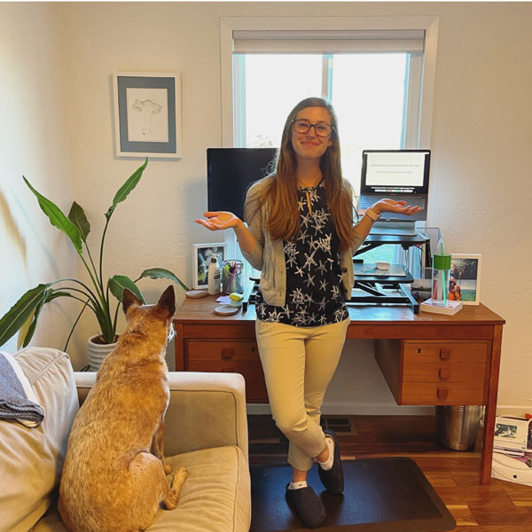 women standing if front of desktop with her dog looking at her