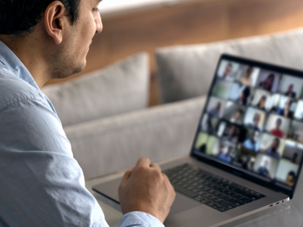 Man using a laptop computer. Meeting in progress with lots of people in a Zoom meeting.